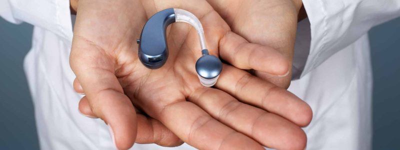 high-angle-hands-holding-hearing-aids